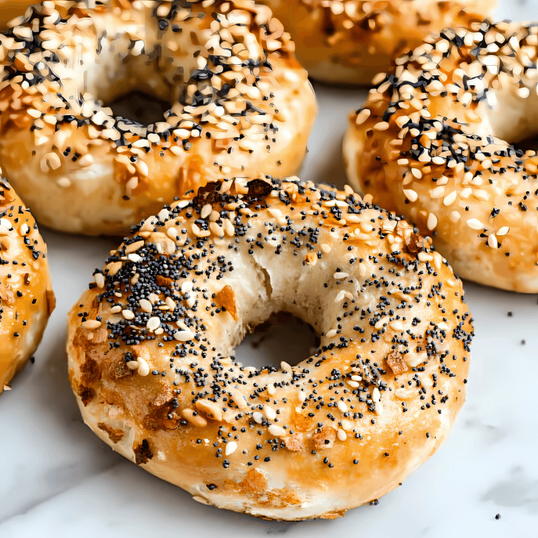 Freshly baked protein bagels made with Greek yogurt, cooling on a rack, with a side of cream cheese.