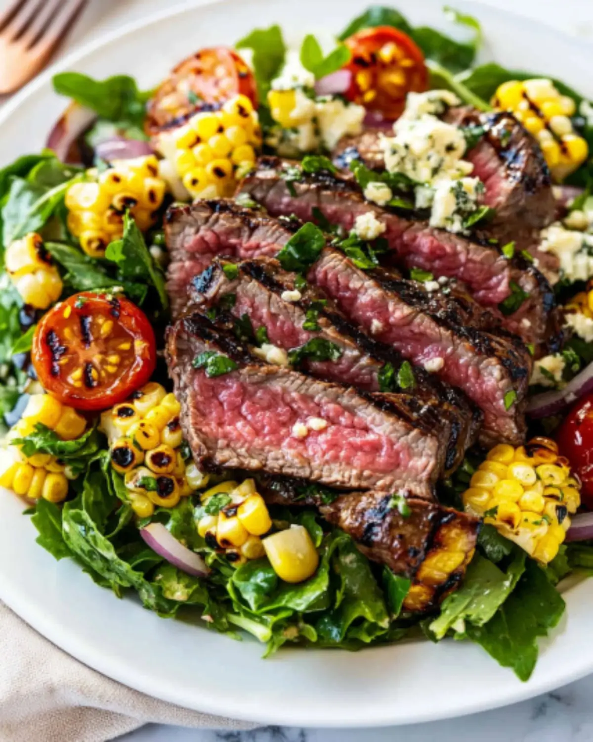 Overhead view of balsamic steak salad with gorgonzola, grilled corn, cherry tomatoes, and lemon slices
