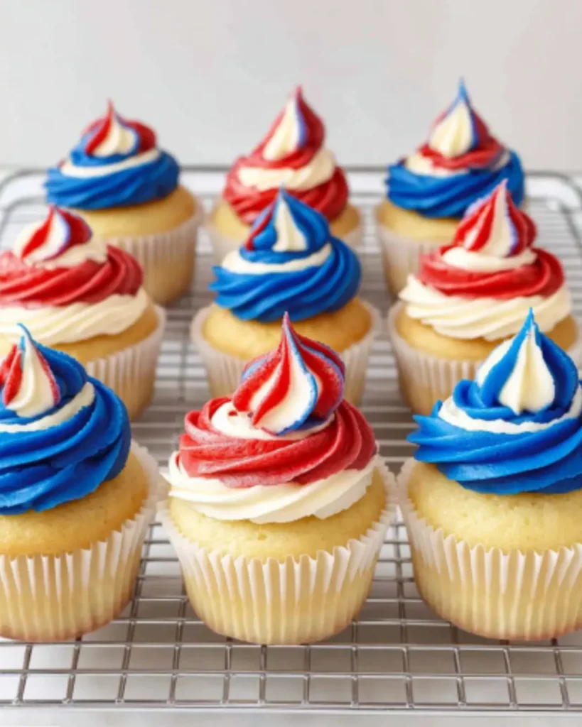 Red, white, and blue 4th of July cupcakes with buttercream frosting on a cooling rack