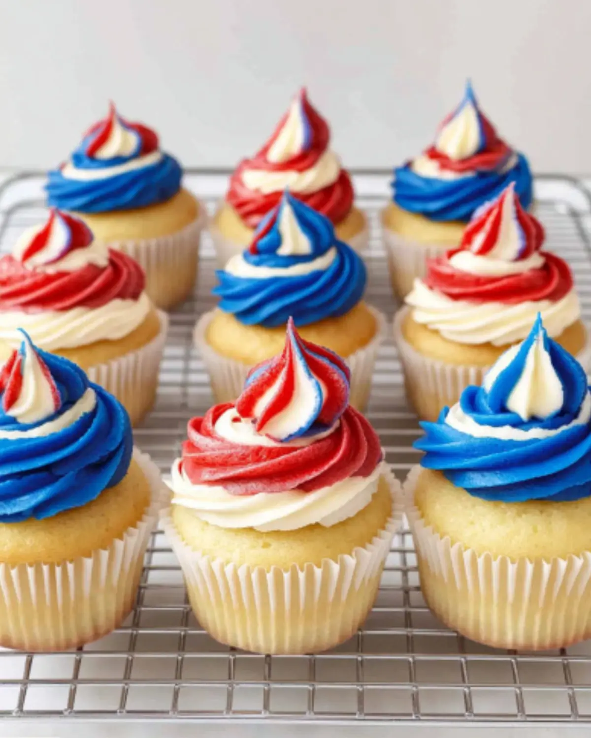 Red, white, and blue 4th of July cupcakes with buttercream frosting on a cooling rack