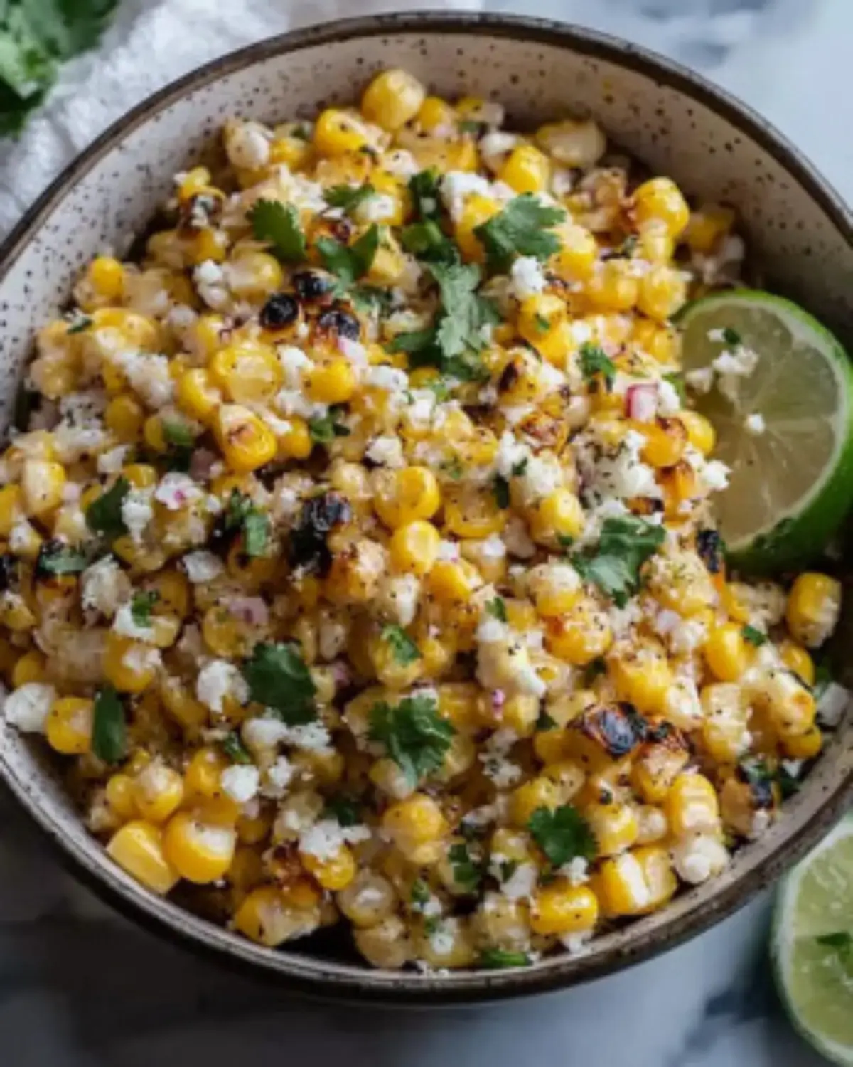 Charred corn salad with cotija cheese, red onion, and cilantro in a rustic bowl