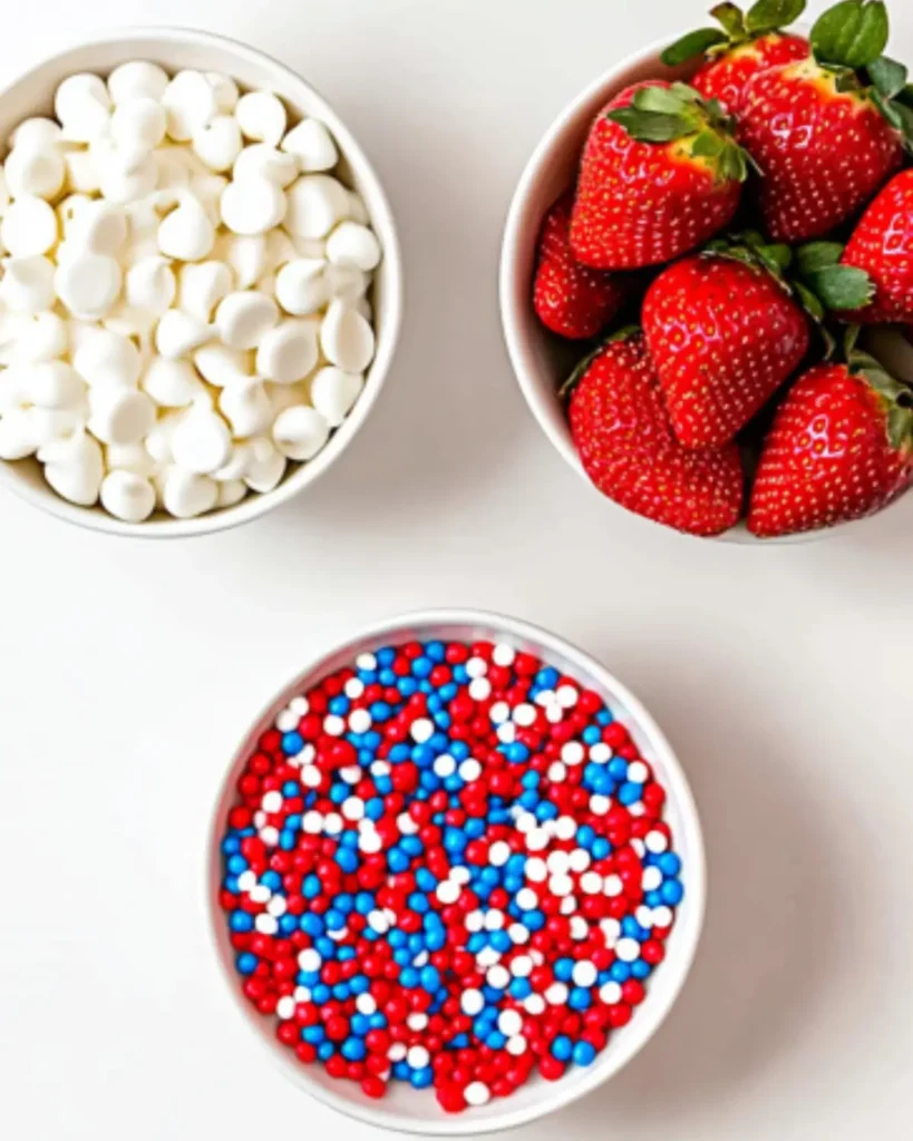 Fresh strawberries, white candy melts, and red, white, and blue sprinkles arranged for making 4th of July chocolate-covered strawberries.