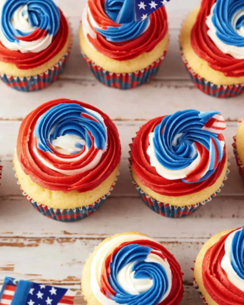 4th of July cupcakes with circular red, white, and blue swirled frosting on a rustic wooden table