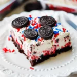No-bake fireworks Oreo cheesecake bars in a baking dish, decorated with Oreos and red, white, and blue sprinkles, patriotic dessert.