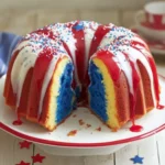 Close-up of Firecracker Red, White and Blue Bundt cake with red and white glaze and colorful sprinkles, on a white plate.