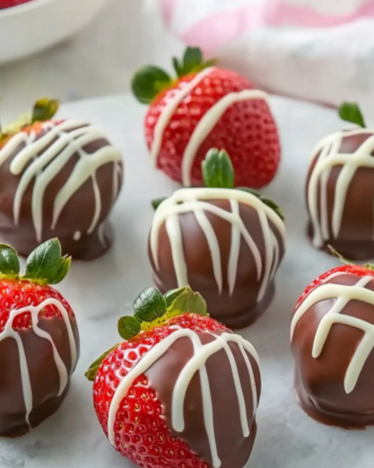 Fresh strawberries dipped in chocolate and drizzled with white chocolate on a white tray