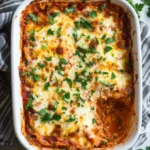 Baked cheesy lasagna in a white rectangular dish with fresh parsley topping