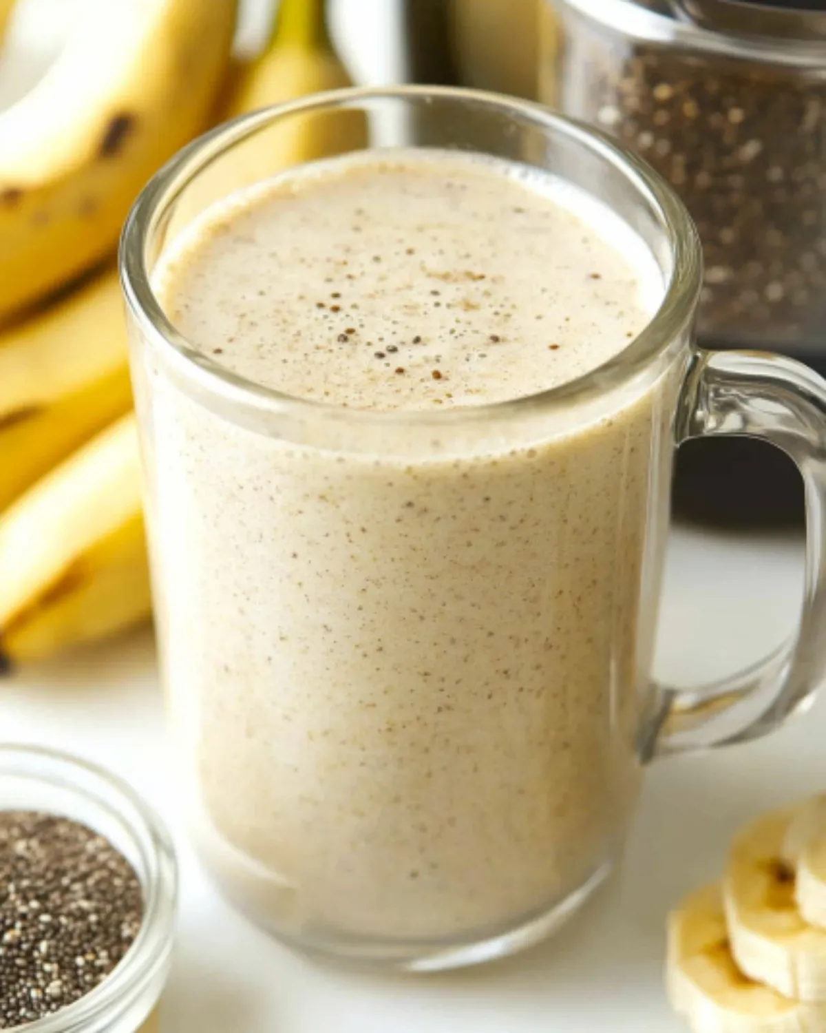 Creamy banana smoothie for weight loss in a clear glass mug with chia seeds and bananas