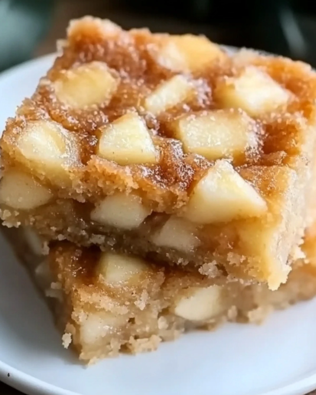 Two stacked squares of soft apple cake filled with golden baked apple pieces