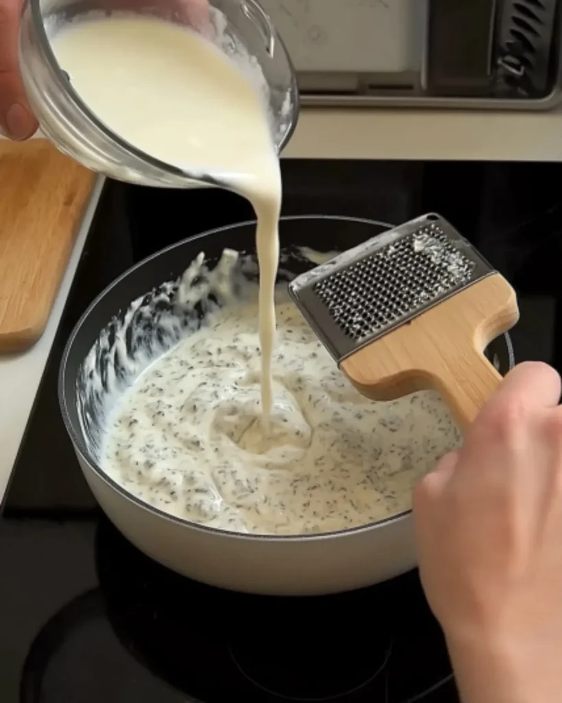 Stirring Greek yogurt into sautéed garlic and herbs for a healthy Alfredo sauce base