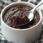 Classic microwave chocolate cake in a white mug on checkered kitchen towel
