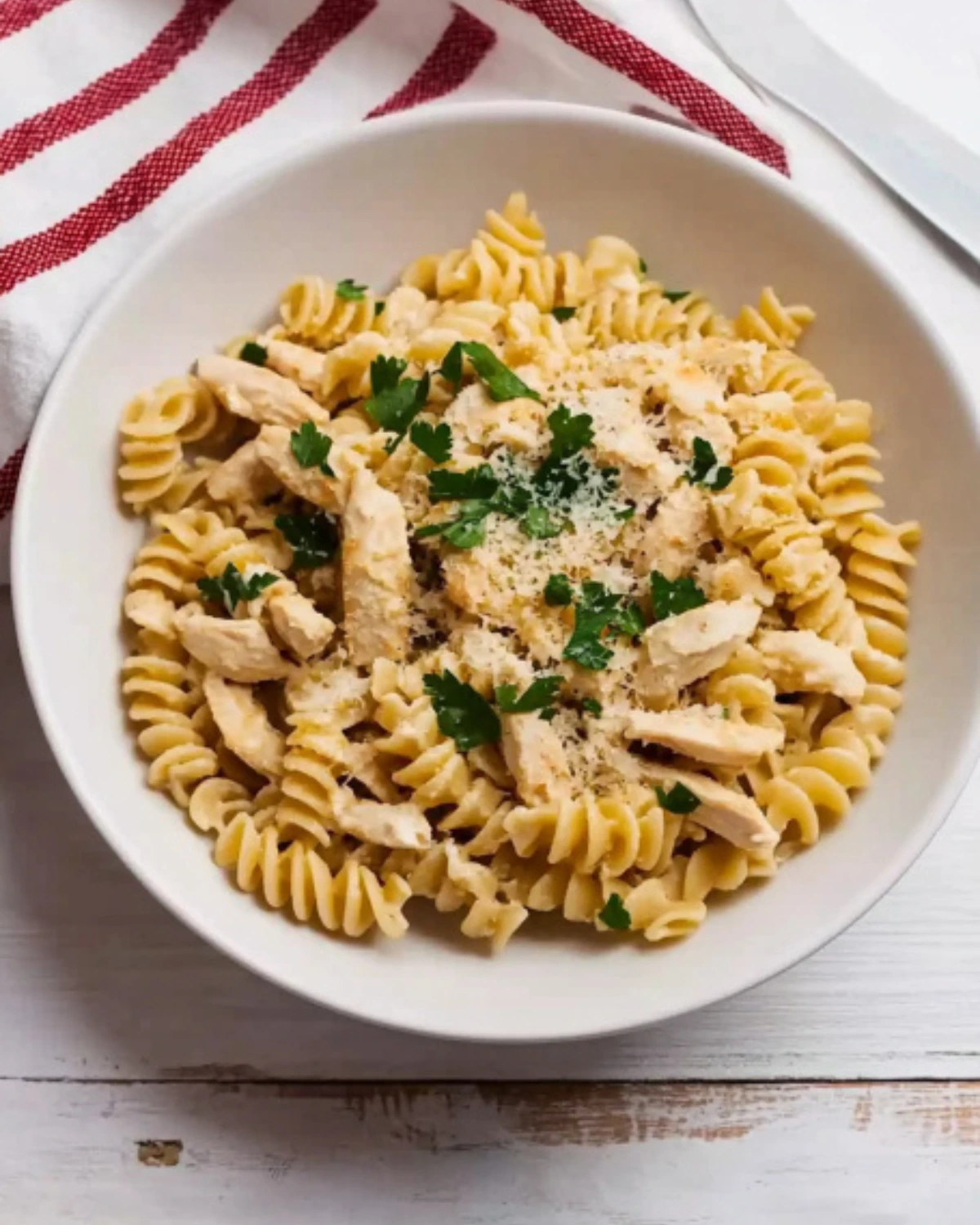 Bowl of creamy garlic parmesan chicken pasta topped with parsley and parmesan