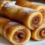 Glazed cinnamon roll-ups stacked on a plate, showing detailed cinnamon swirls and flaky pastry edges.