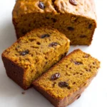 Sliced healthy no sugar pumpkin banana bread with raisins on a white surface