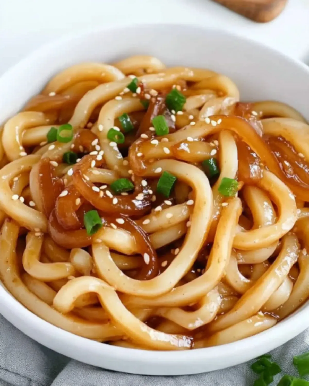 Udon noodles tossed with garlic soy sauce, caramelized onions, and fresh chives in a wok
