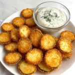 Crispy air fryer fried pickle chips with golden panko crust and creamy dill dip on a white plate