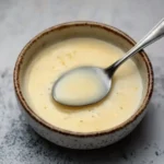 Lemon beurre blanc in a ceramic bowl with spoon, smooth French butter sauce for seafood