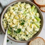 Bowl of healthy egg salad made with Greek yogurt, celery, and parsley served with sliced bread