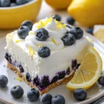 Indulge in a refreshing blueberry dessert, featuring a creamy filling on a graham cracker crust, topped with whipped cream, fresh blueberries, and zesty lemon. A perfect treat to brighten up any day