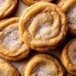 Golden-brown freshly baked cookies with a light sugar coating on parchment paper.