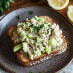 Open-faced tuna salad sandwich with celery, green onions, and herbs on multigrain toast.