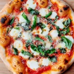 Freshly baked Margherita pizza topped with mozzarella, tomato sauce, and basil on a wooden surface