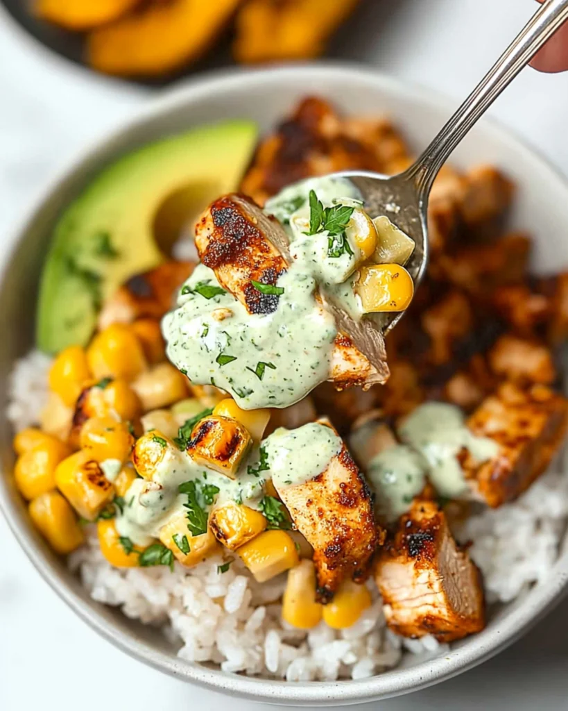 Spoonful of creamy grilled chicken burrito bowl with avocado, corn, and cilantro lime dressing