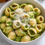 Overhead view of creamy broccoli pasta shells topped with parmesan in a white bowl