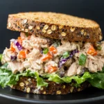 Creamy tuna salad sandwich with colorful vegetables on oat-crusted bread