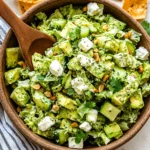 Fresh chopped green salad with avocado, feta, pepitas, and green goddess dressing in a rustic bowl
