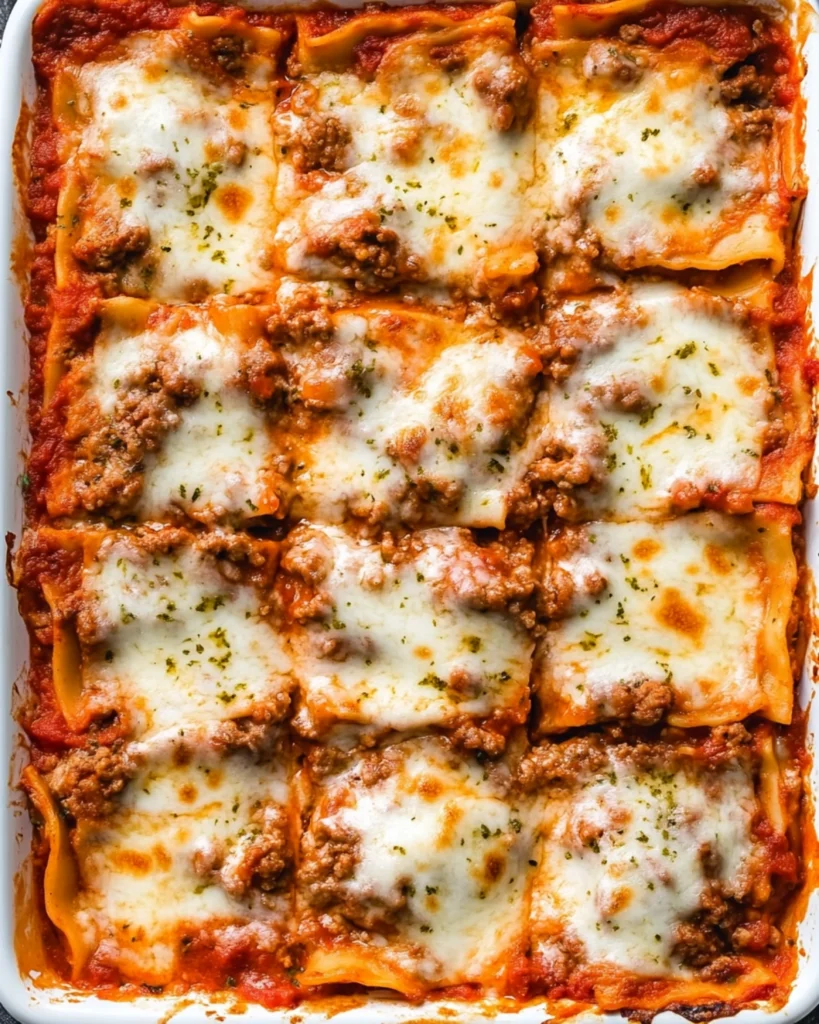 Overhead shot of a freshly baked beef lasagna cut into squares in a white baking dish