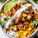 Healthy grilled chicken burrito bowl with corn, avocado, cilantro, and rice topped with creamy dressing