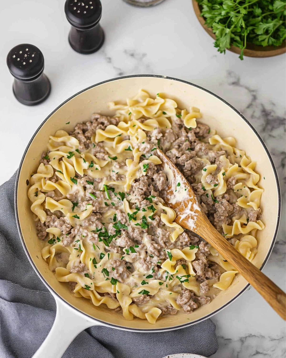 Creamy beef and egg noodle skillet with parsley garnish and white spatula in a rustic pan.