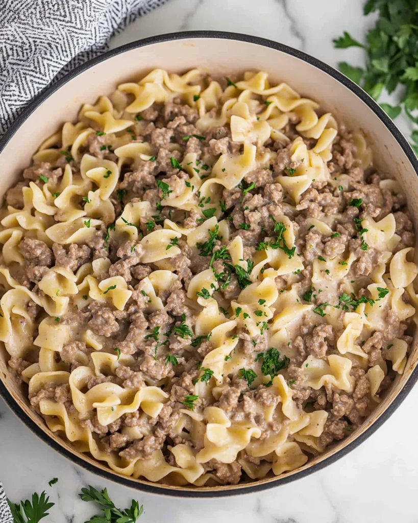 Creamy beef and egg noodle skillet with parsley garnish in a rustic pan.