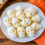 Creamy white skull-shaped Halloween candies arranged on a plate