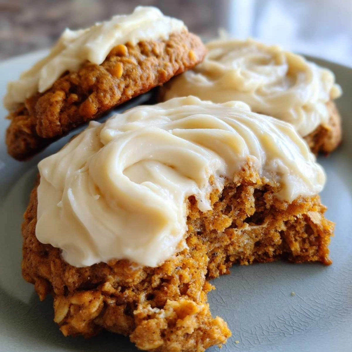Soft spiced cookie with creamy frosting and a bite taken out on a plate