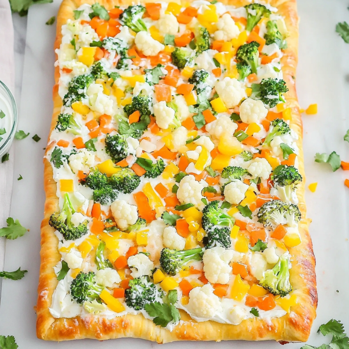 Rectangular crescent roll veggie pizza topped with broccoli, peppers, cauliflower, and carrots.