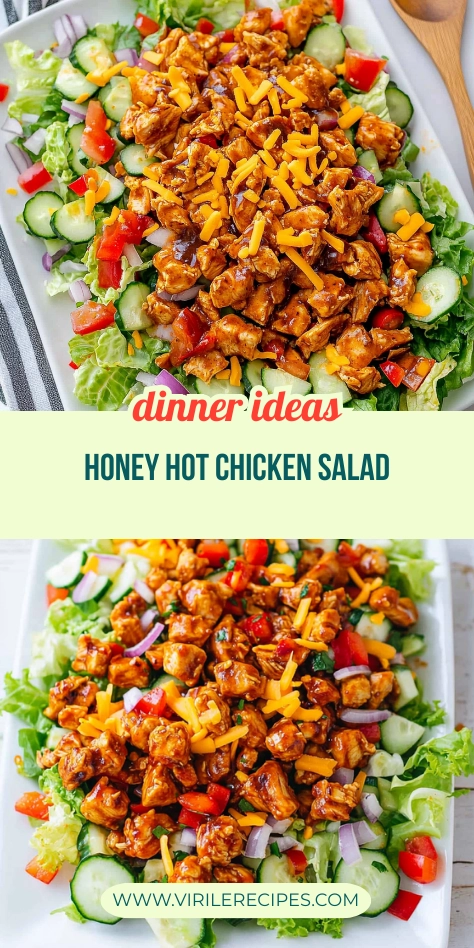 Honey hot chicken salad with lettuce, cucumbers, bell peppers, red onions, and cheddar cheese on a white plate.