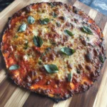Zucchini crust pizza with mozzarella cheese and fresh basil on a wooden board