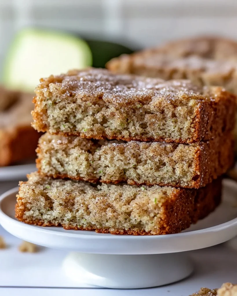Stack of zucchini bread slices with cinnamon sugar crust on a white cake stand

