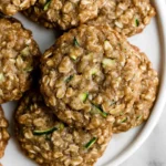Side view of zucchini oatmeal cookies stacked on a plate with visible oats and shredded zucchini