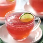 Close-up of Cosmopolitan Party Punch in a clear glass teacup with lime slice garnish