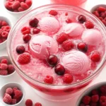 Festive pink sherbet punch with raspberries and cranberries in a glass punch bowl