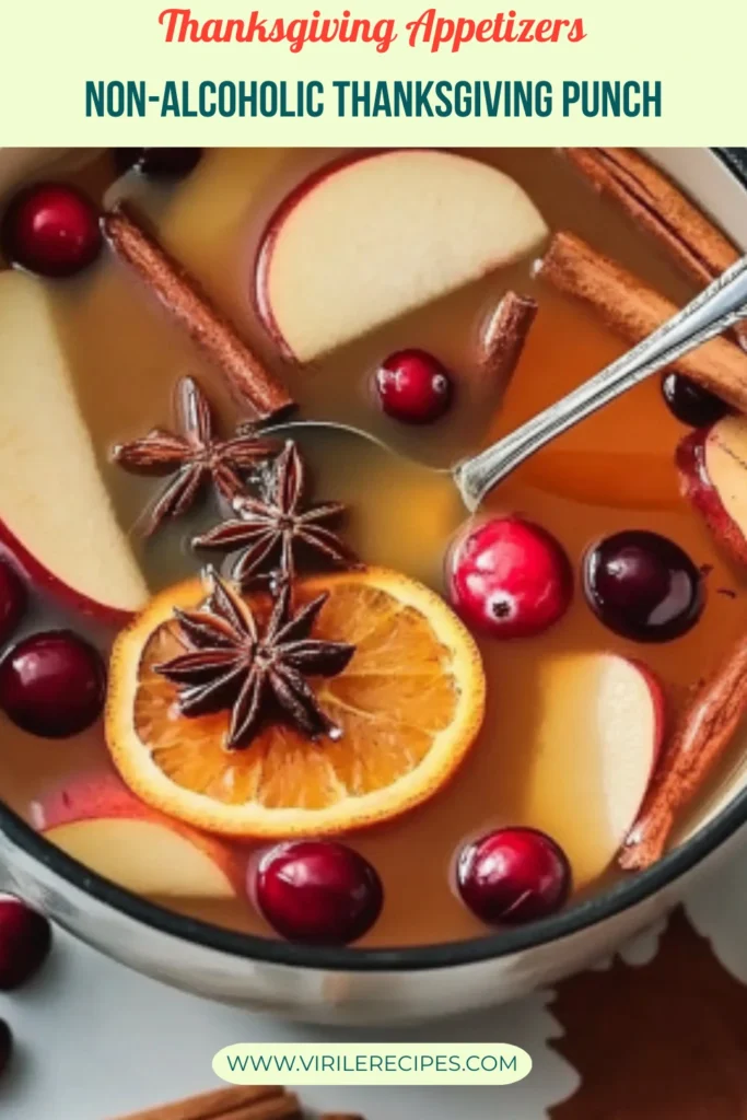 Non-alcoholic Thanksgiving punch with sliced apples, oranges, cranberries, and cinnamon sticks