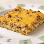Slice of sausage egg breakfast casserole with melted cheese on top.