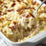 Cheesy chicken bacon pasta bake being served with a spoon showing a gooey cheese pull.