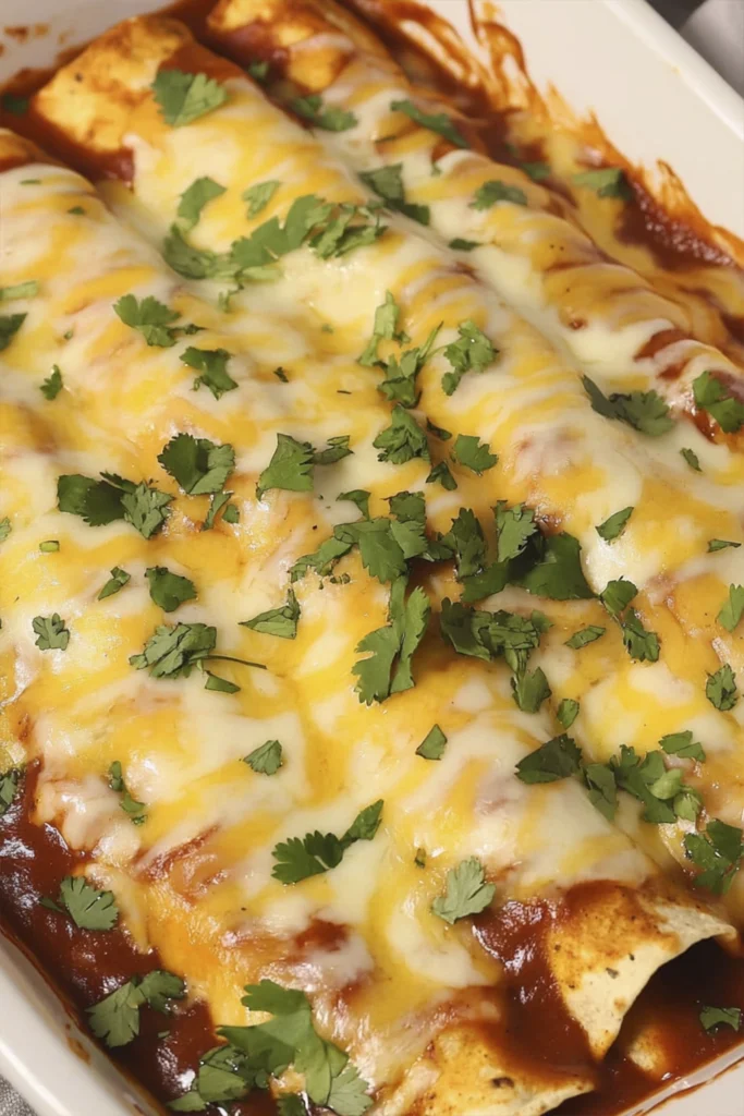 Freshly baked cheesy chicken enchiladas topped with melted cheese and cilantro in a casserole dish.