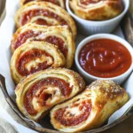 Crispy pepperoni and cheese stromboli slices with marinara dipping sauce on parchment paper.