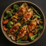 Asian stir-fry with soy-glazed dumplings, broccoli, carrots, mushrooms, and asparagus in a ceramic bowl