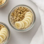 Glass jar of banana overnight oats topped with granola and banana slices.
